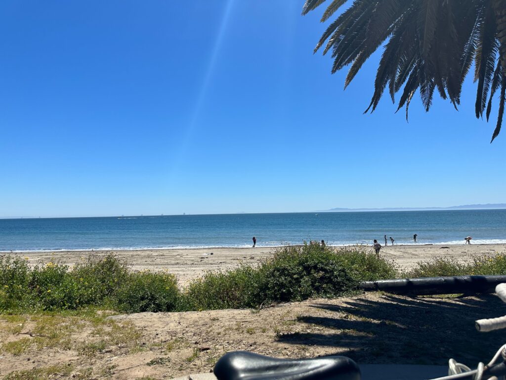 A landscape photo of a beach with many people in the distance at the water.