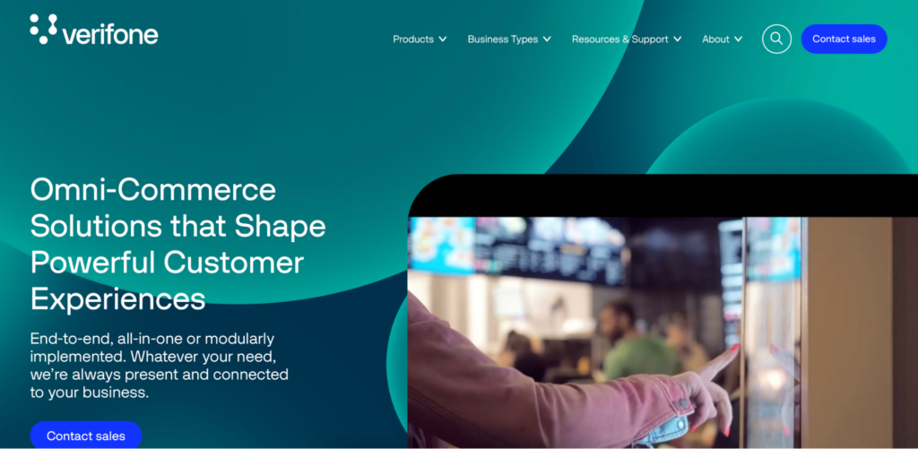A preview of Paddle alternative 2Checkout by Verifone's homepage, a green webpage with an image of someone touching a touch screen.