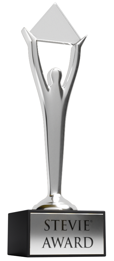 A silver trophy of a humanoid shape with its hands above its head holding a pyramid.